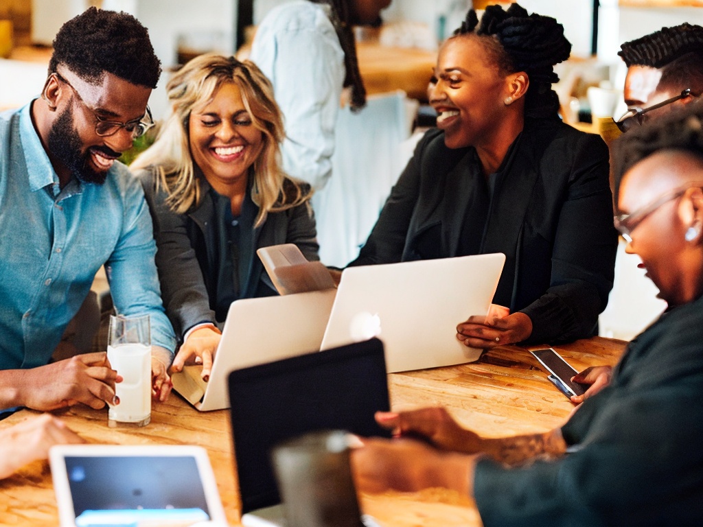 RAW photo, a close-up of a diverse group of people collaborating over digital devices showcasing no-code AI tools, warm ambient light creating a friendly workspace atmosphere, 8k UHD, high resolution, realistic photo, soft focus, Nikon Z6